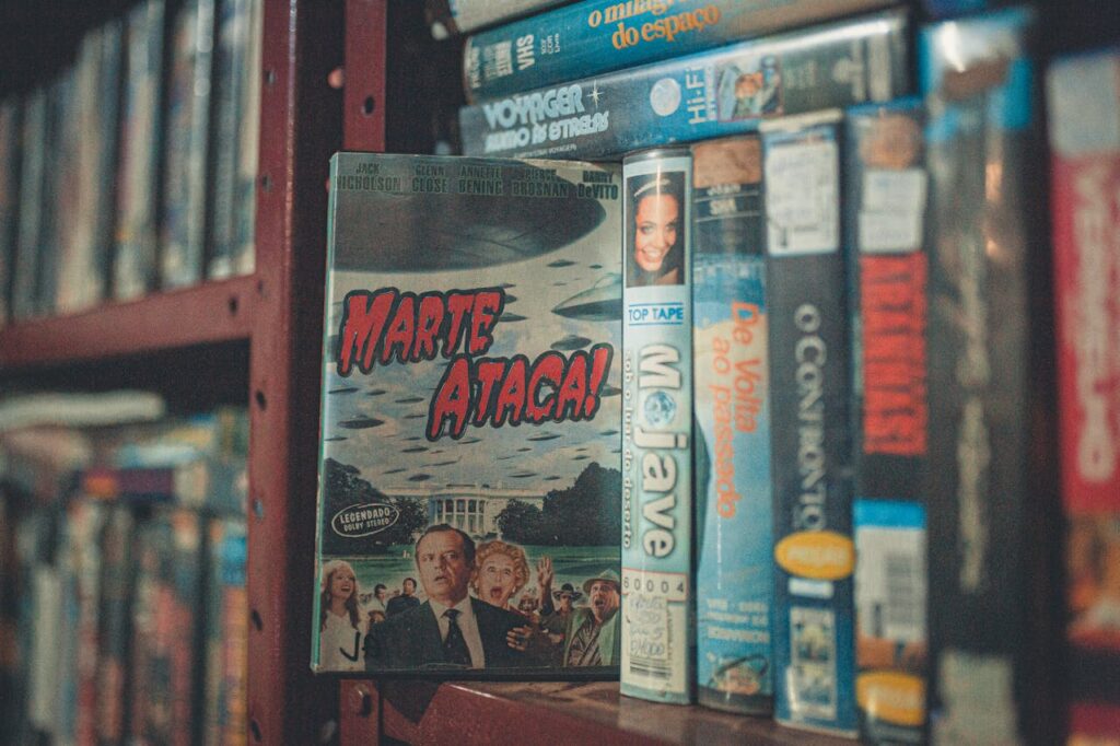 A nostalgic display of vintage VHS tapes with classic movie titles on a wooden shelf indoors.